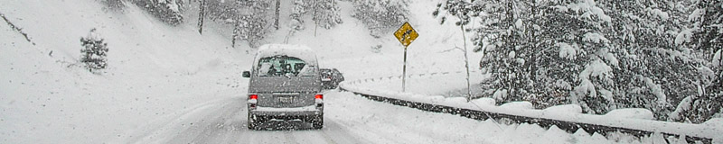 vehicles on a mountain road in heavy snow