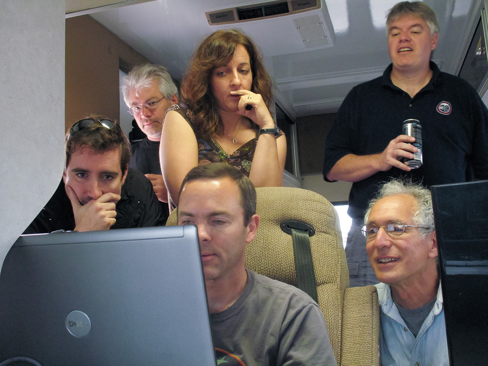 Multiple people conferring over a laptop.