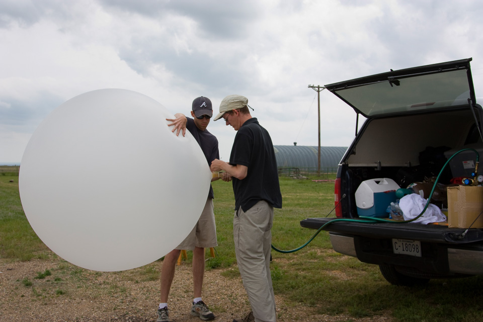 Two people preparing a weather balloon for launch.