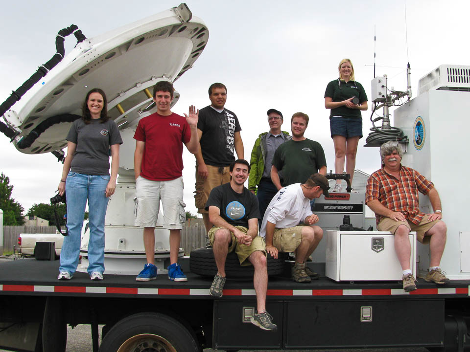 student crew members plus advisors facing camera on the bed of a truck carrying a mobile radar